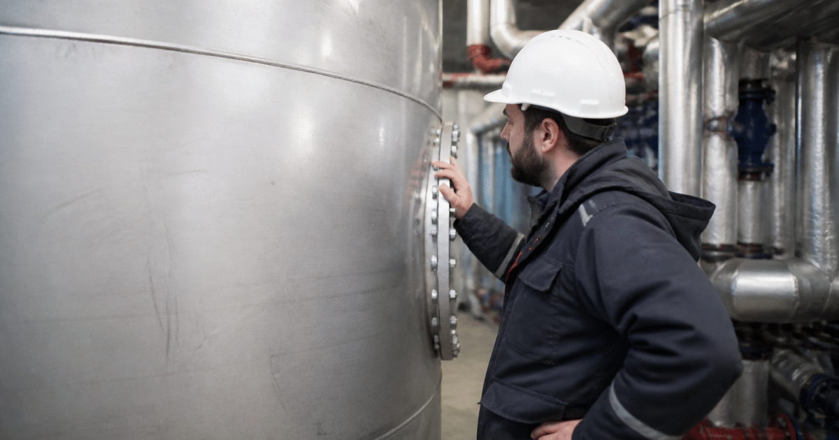 Technicien inspectant reservoir metallique eau froide immobile