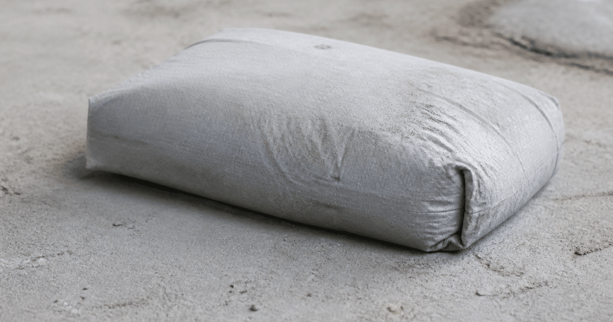 Sac ciment gris posé sur surface beton poudreuse