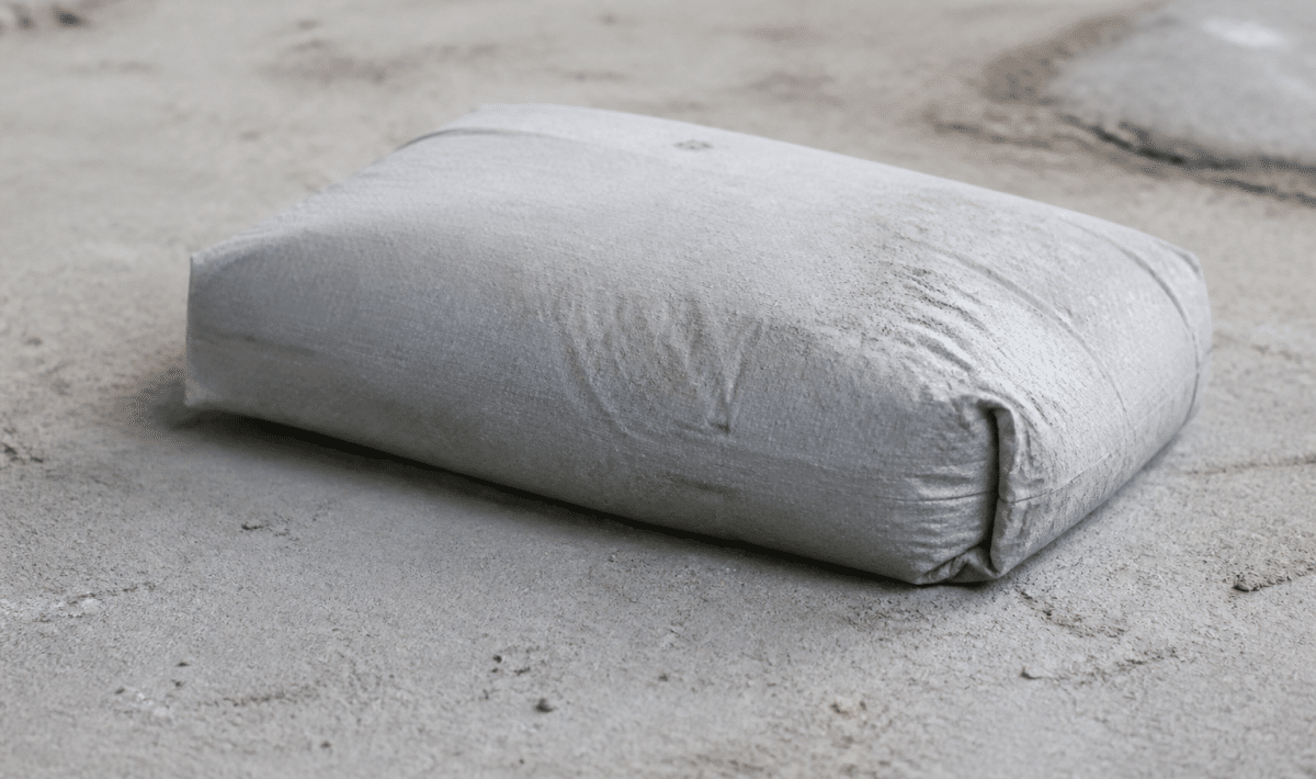 Sac ciment gris posé sur surface beton poudreuse