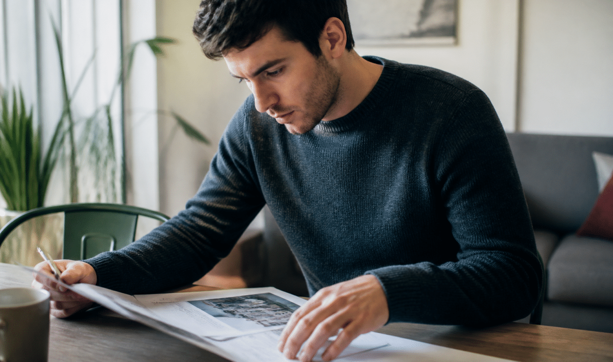 Locataire consultant document immobilier sur table avec stylo