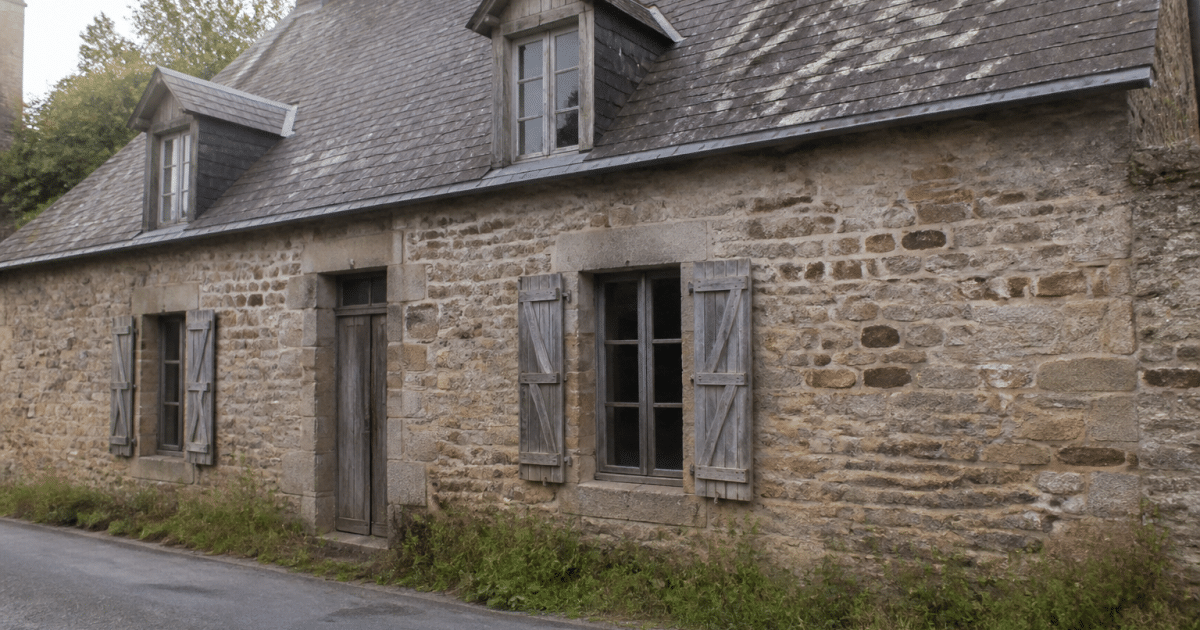 Ancienne maison en pierre avec facade usee et toiture patinee