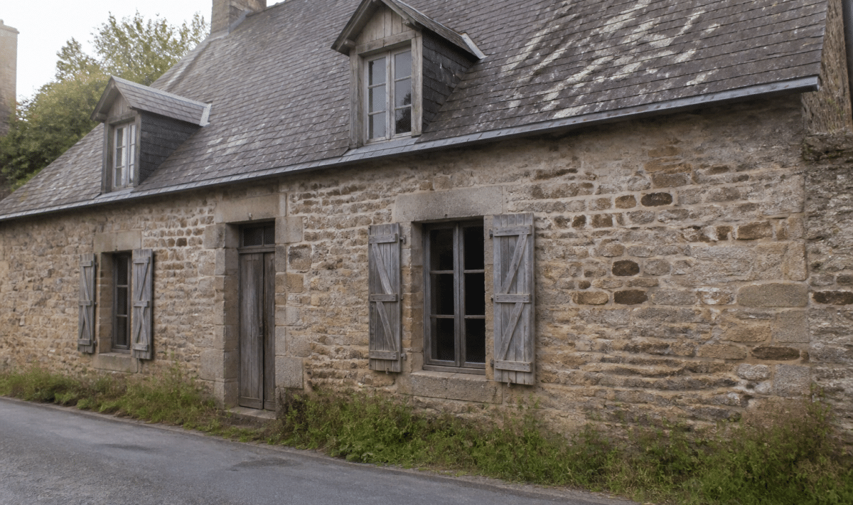 Ancienne maison en pierre avec facade usee et toiture patinee
