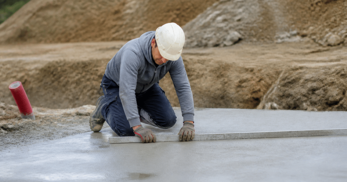 Ouvrier mesurant dalle beton grise avec regle metallique