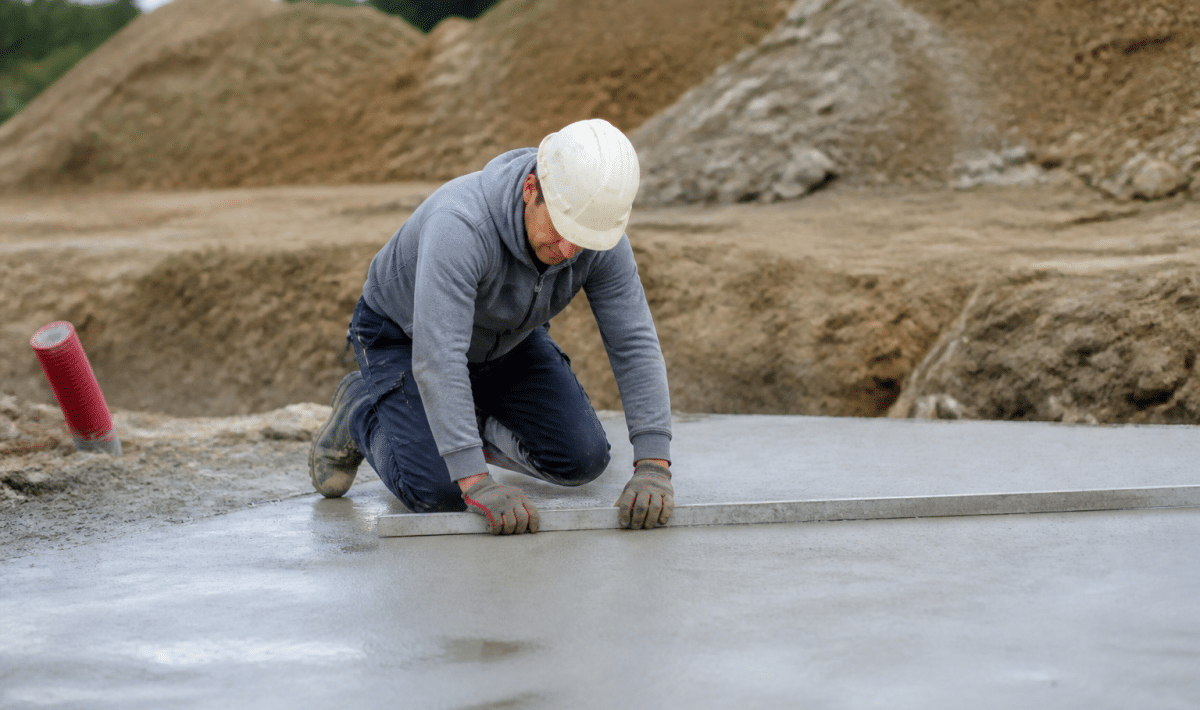 Ouvrier mesurant dalle beton grise avec regle metallique