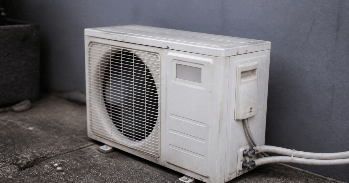 Unite climatique defaillante posee au sol contre mur gris