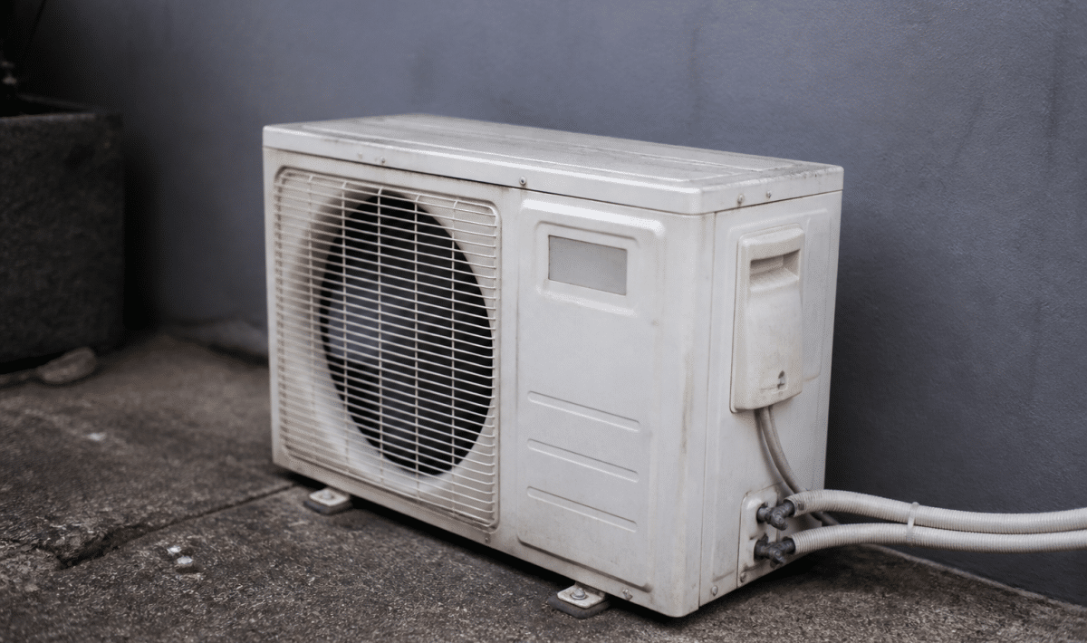 Unite climatique defaillante posee au sol contre mur gris