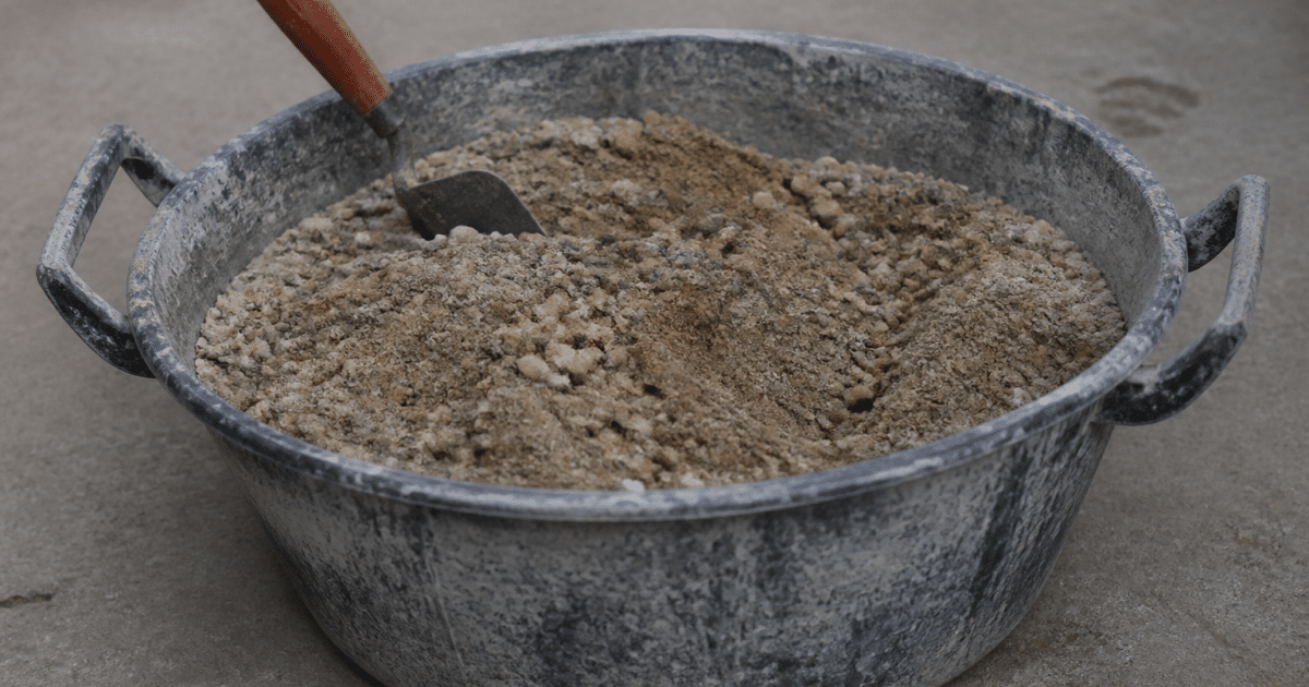 Seau de melange beton sable gravier pose sur sol gris