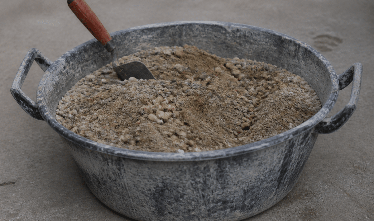 Seau de melange beton sable gravier pose sur sol gris