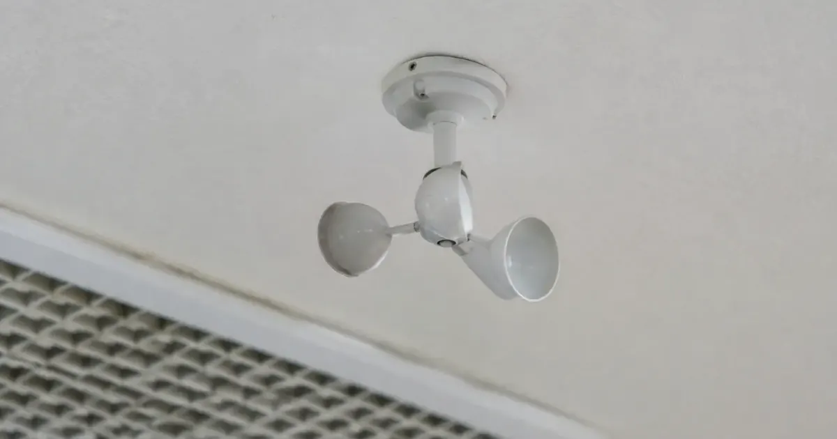 Main tenant anemometre pres grille blanche au plafond