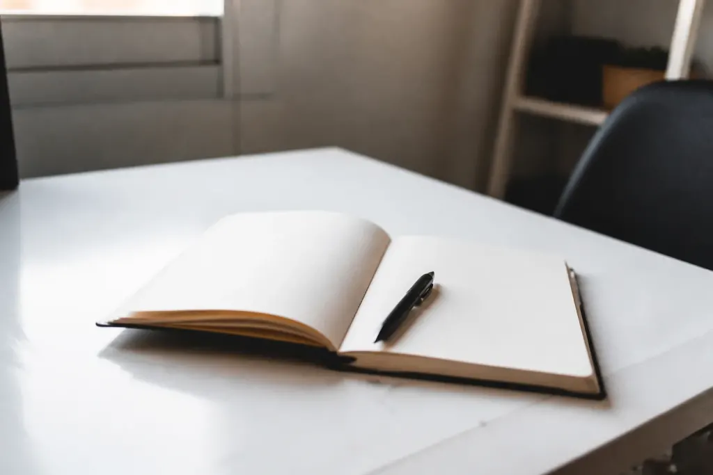 Carnet ouvert et stylo sur un bureau blanc