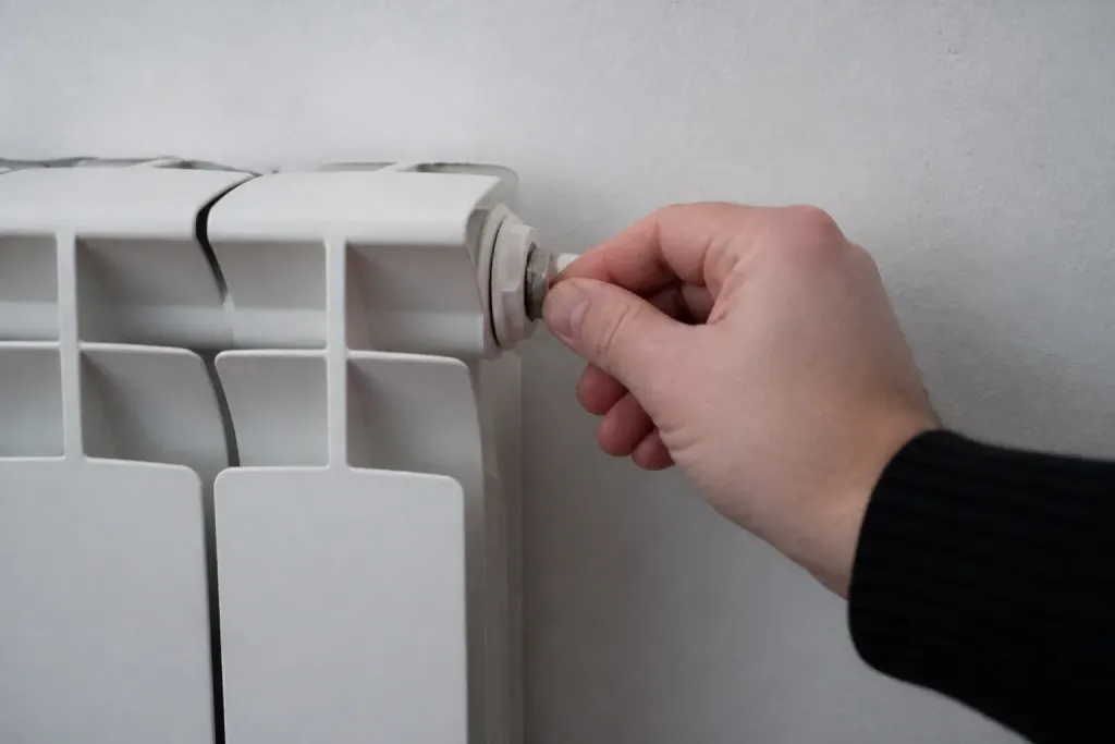 Main tenant une cle de purge sur radiateur blanc