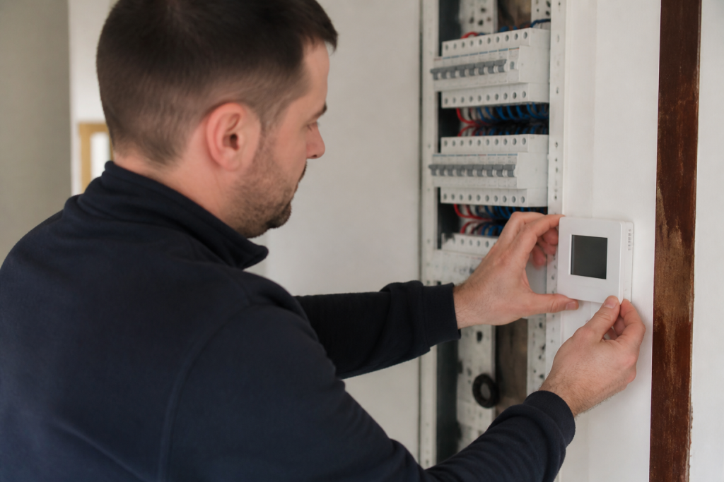 Electricien installe thermostat blanc au tableau