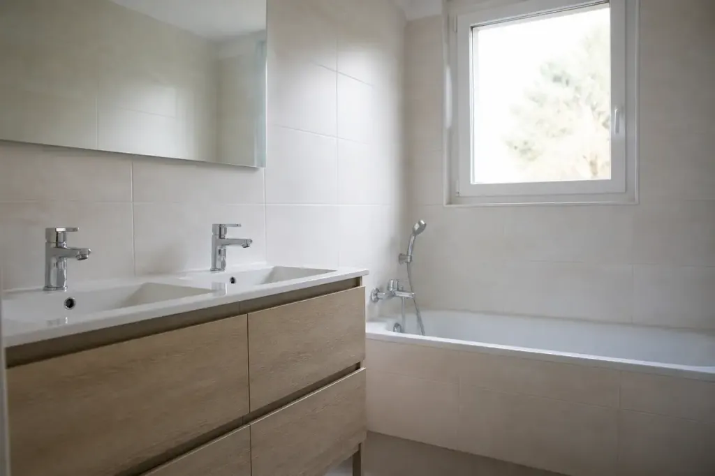 Lavabo double et baignoire blanche dans une piece carrelee