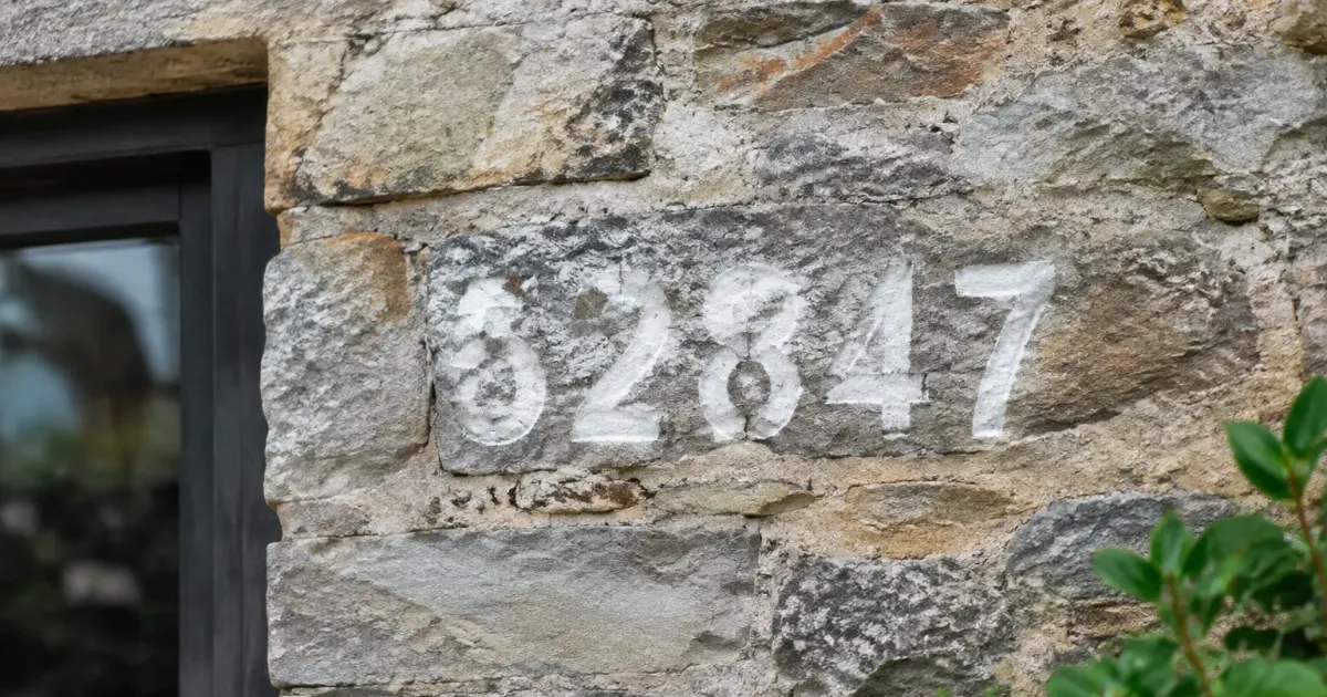 Numero adresse cinq chiffres peints blanc mur pierre