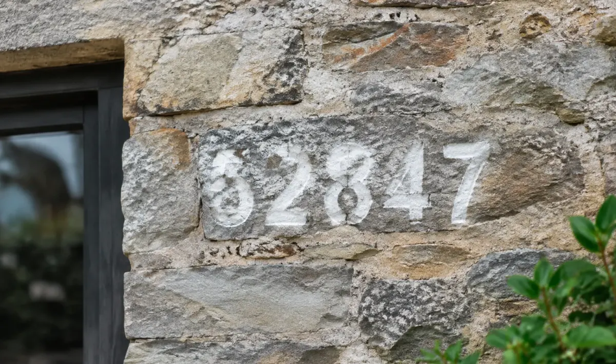 Numero adresse cinq chiffres peints blanc mur pierre