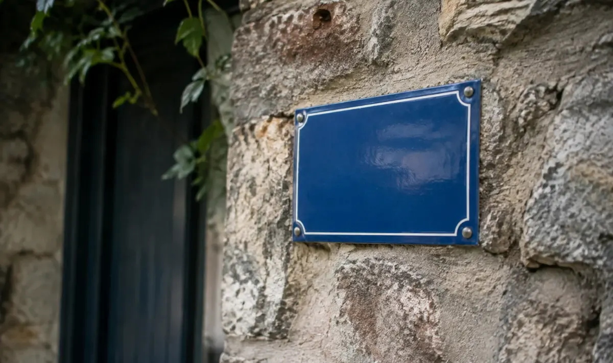 Plaque bleue fixee sur mur en pierre ancienne