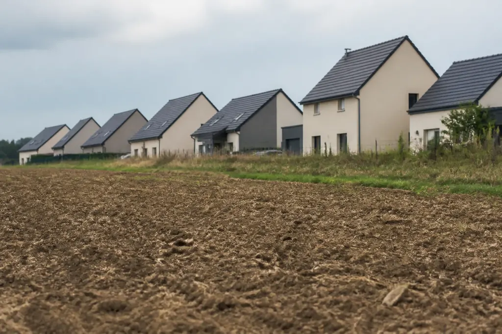 Rangee de maisons neuves bordant un champ laboure