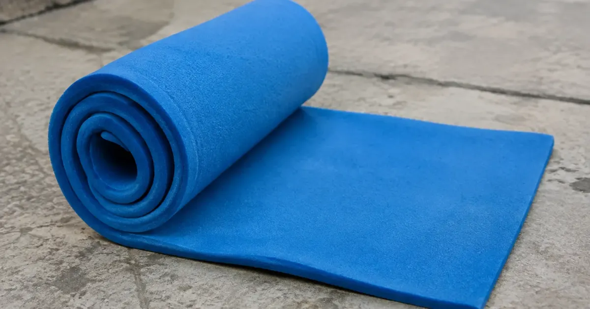 Rouleau de mousse bleue ouvert sur dalle beton grise